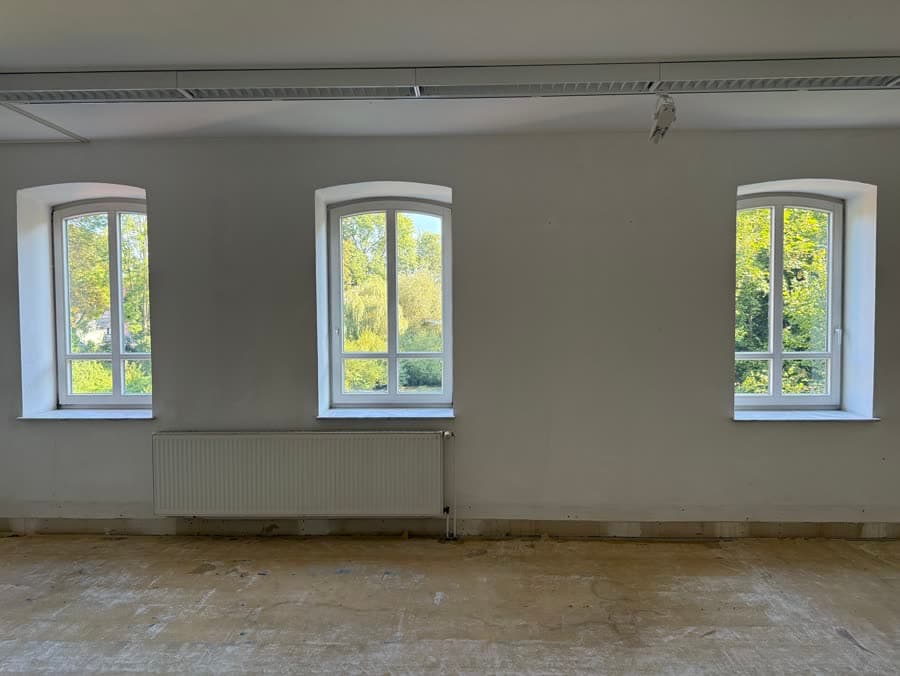 Heller Raum der freien Erdgeschossfläche: drei Bogenfenster mit Blick ins Grüne